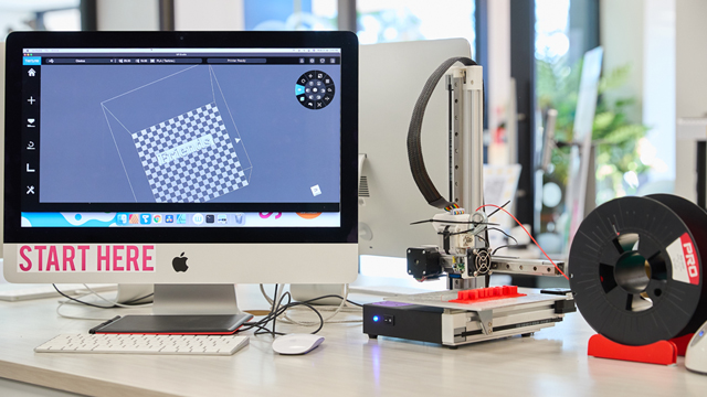 Image of a mac computer and a 3D printer on a table
