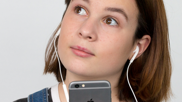 Teenage girl with headphones listening to audio.