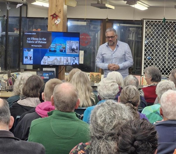 Image of a man presenting to a group of people about Petone