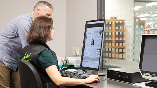 Two people looking at a microfiche on a computer screen.