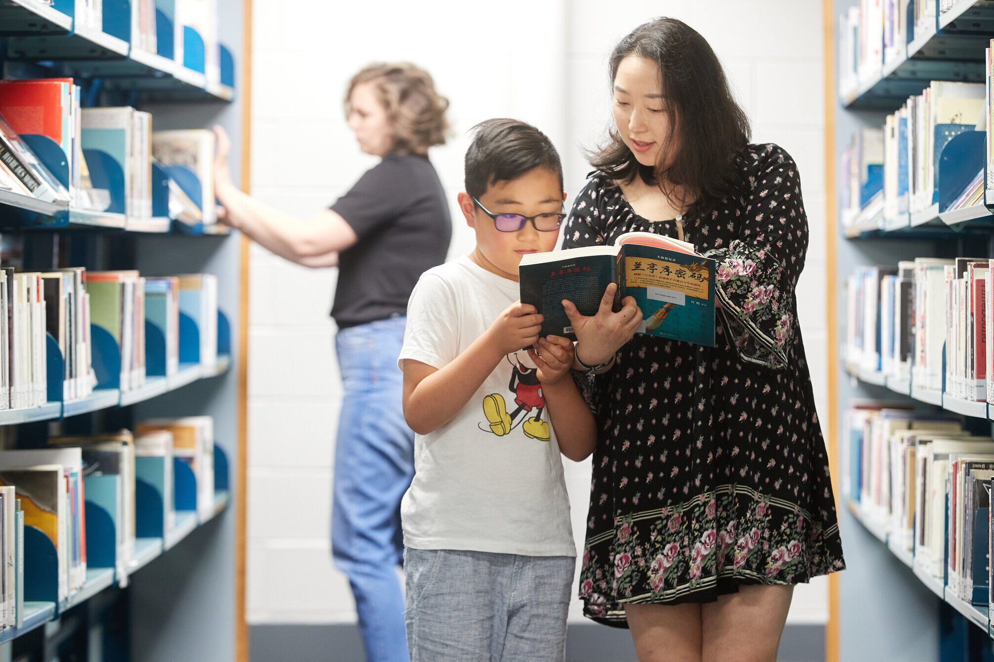 chinese mother shows son a book in chinese