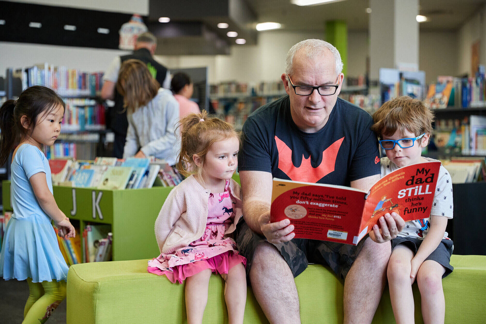 father reads book to 2 children