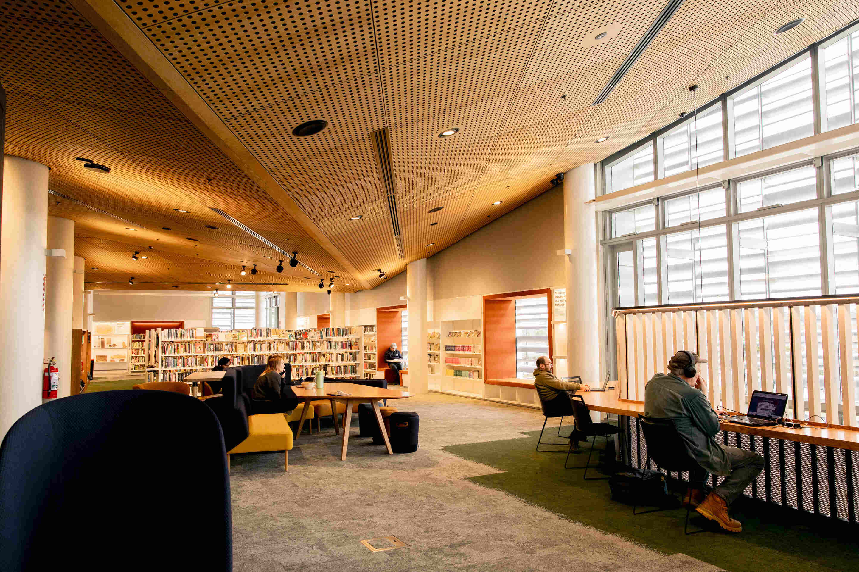 Library interior showing study areas and book shelves dappled by light