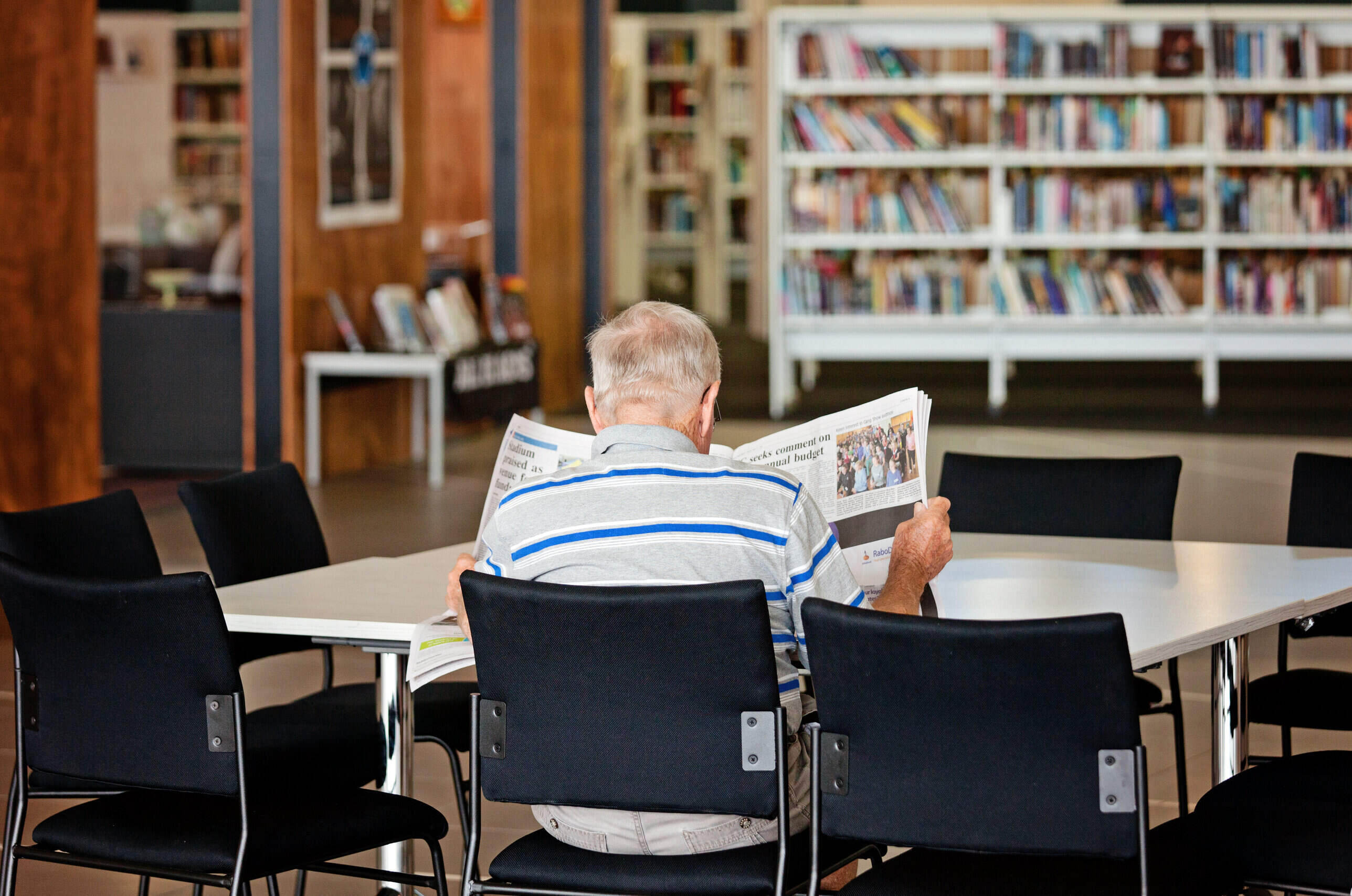 Image of man reading newspaper at a table