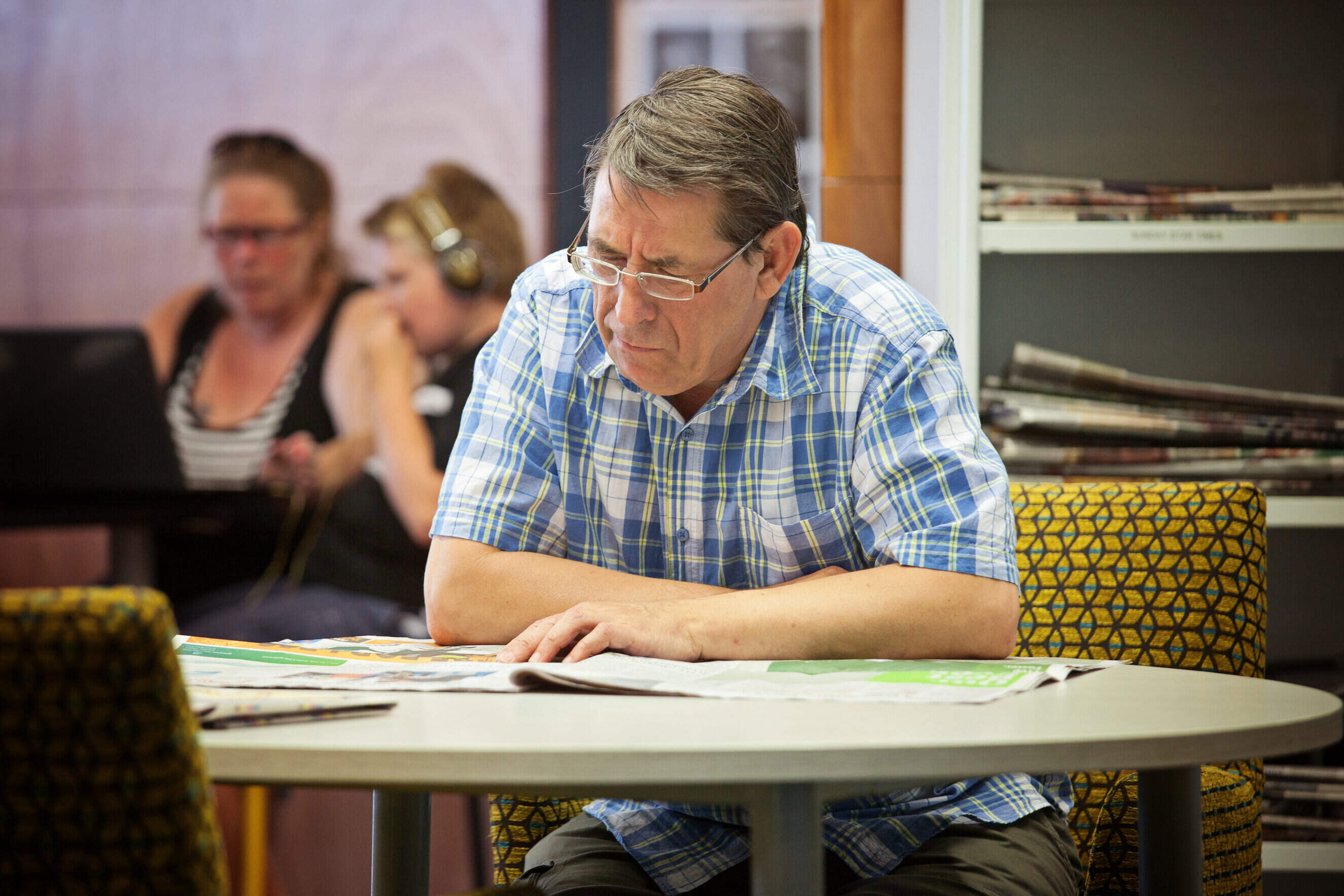 Image of man reading newspaper at a table