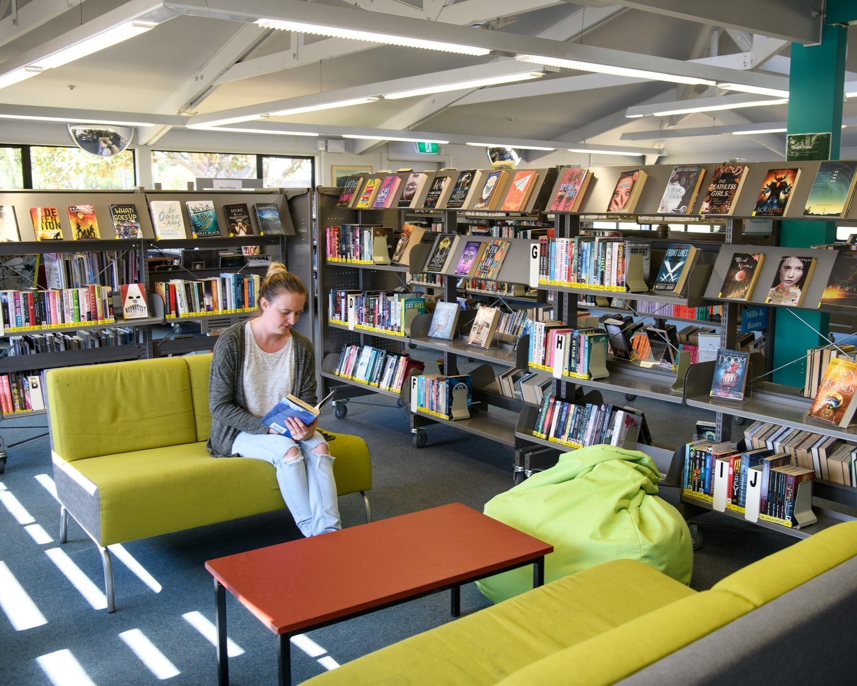 Image showing a quiet library space with someone sitting on a couch and reading